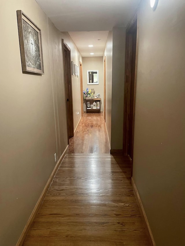 corridor with baseboards and wood finished floors