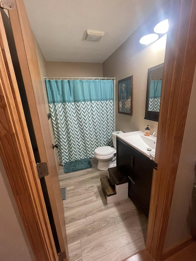 full bath with vanity, a shower with curtain, visible vents, toilet, and wood finished floors