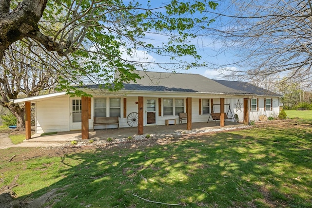 back of property featuring a porch, a carport, a yard, and metal roof