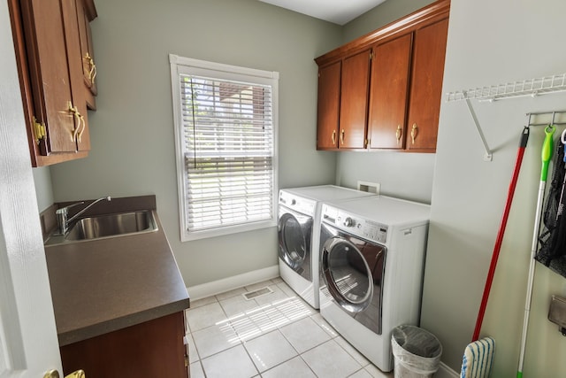 laundry room with baseboards, light tile patterned floors, washing machine and dryer, cabinet space, and a sink