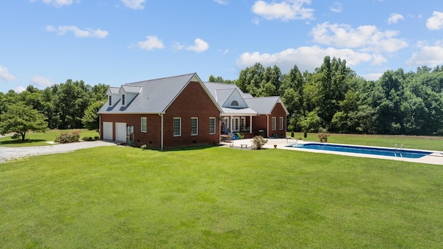 back of property featuring an outdoor pool, a patio, a garage, and a lawn