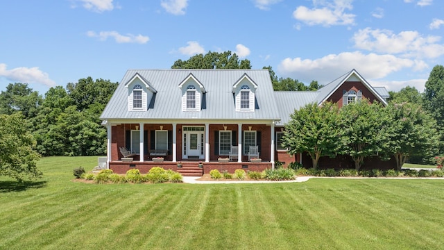 cape cod home with brick siding, a front yard, a porch, and metal roof