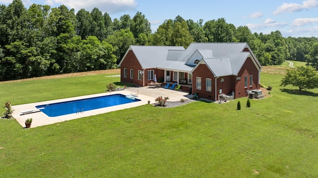 pool featuring a patio, a diving board, central AC unit, and a lawn
