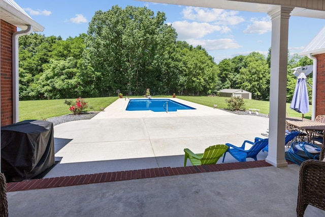 outdoor pool with area for grilling, a patio, an outbuilding, and a lawn