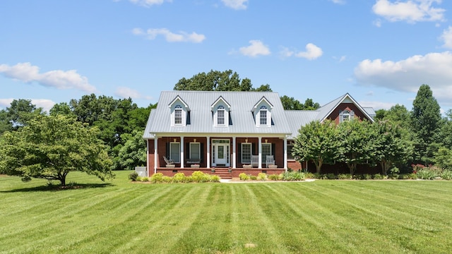 cape cod house featuring a porch, a front yard, and brick siding