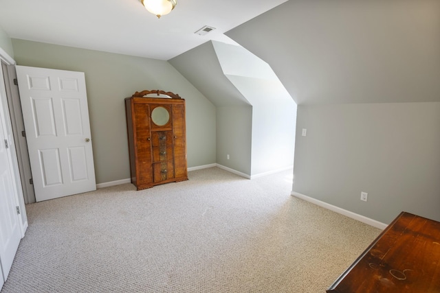 additional living space featuring visible vents, baseboards, vaulted ceiling, and light carpet