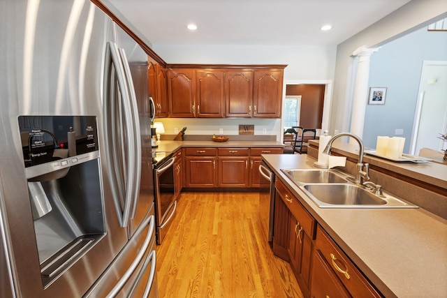 kitchen featuring decorative columns, recessed lighting, a sink, stainless steel appliances, and light wood finished floors