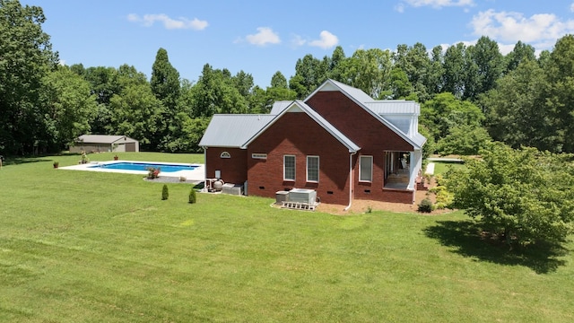 rear view of property featuring an outdoor pool, a yard, metal roof, and brick siding