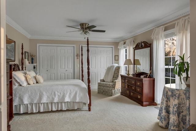 bedroom with two closets, ceiling fan, ornamental molding, and carpet