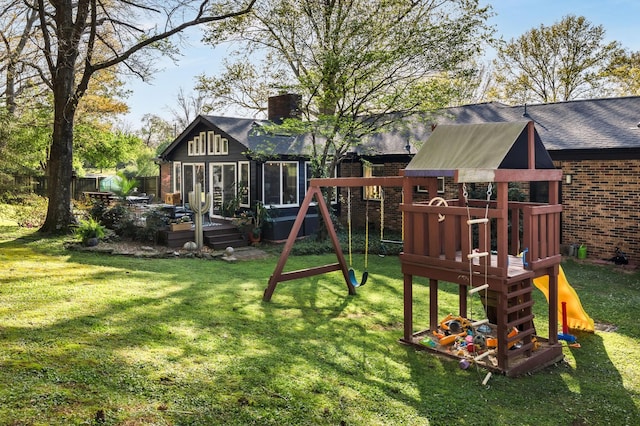 view of playground with a wooden deck, fence, and a lawn