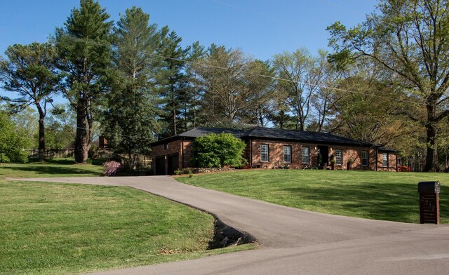 view of front of home featuring brick siding, driveway, and a front lawn