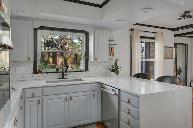 kitchen featuring tasteful backsplash, a peninsula, ornamental molding, dishwasher, and a sink
