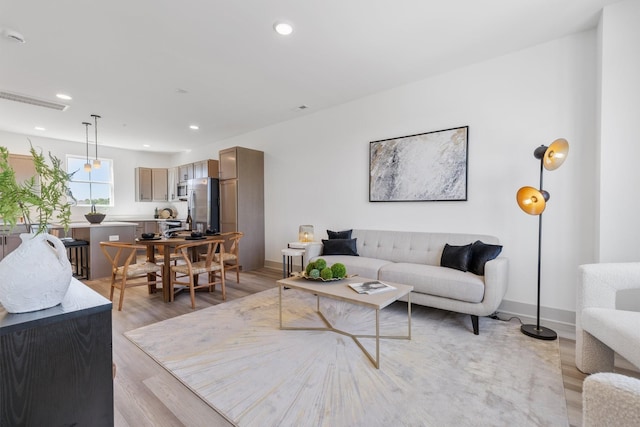 living room with light wood-style flooring, recessed lighting, and baseboards