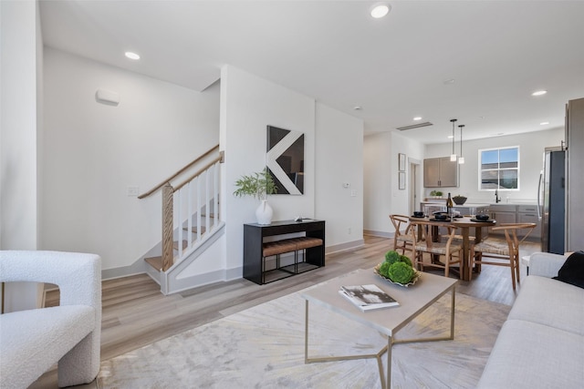 living area with stairway, baseboards, light wood finished floors, and recessed lighting