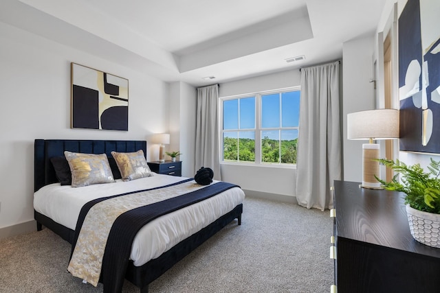 carpeted bedroom featuring visible vents, baseboards, and a tray ceiling