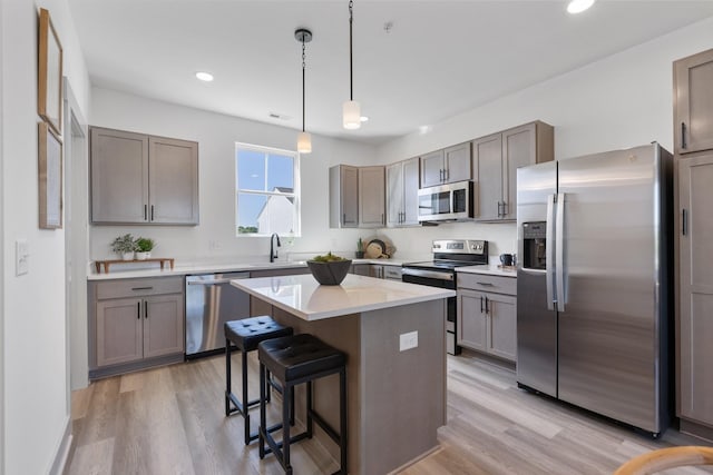 kitchen with stainless steel appliances, light wood-style floors, a center island, and a breakfast bar area