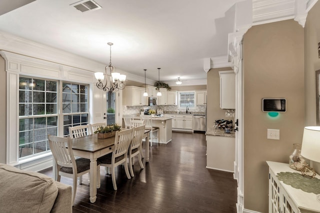 dining room featuring visible vents, baseboards, ornamental molding, a chandelier, and dark wood finished floors