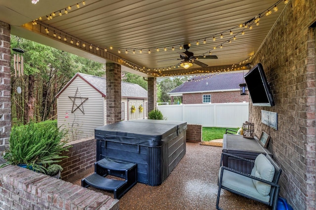 view of patio / terrace with a hot tub, fence, an outbuilding, and ceiling fan