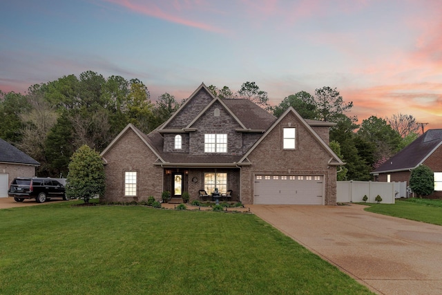 traditional-style house with a front yard, fence, brick siding, an attached garage, and driveway