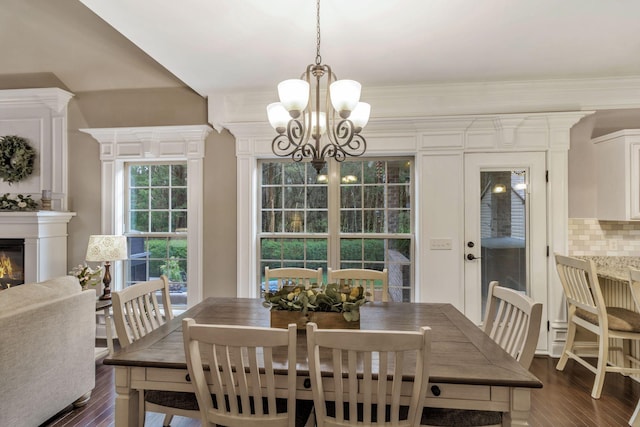 dining room with a chandelier, a glass covered fireplace, dark wood-type flooring, and crown molding