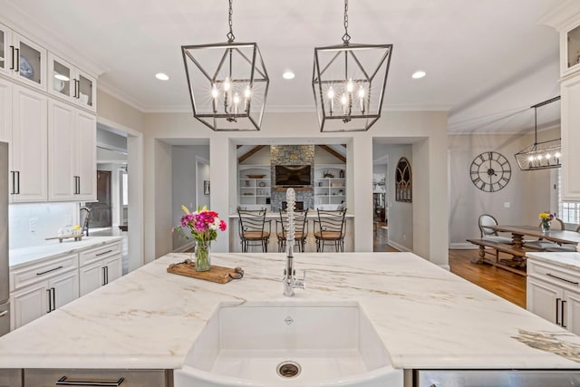 620 Williamson County Line Rd, Fairview, TN 37062 - kitchen featuring a notable chandelier, crown molding, a center island with sink, wood finished floors, and light stone countertops