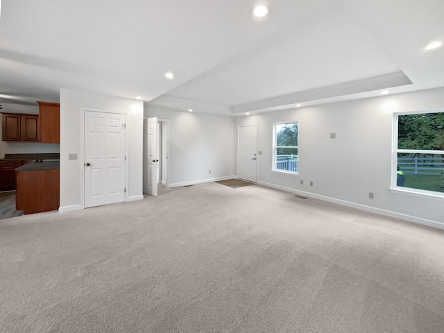 unfurnished living room with a raised ceiling, baseboards, and recessed lighting