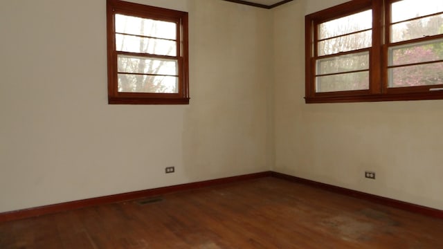 empty room featuring visible vents, baseboards, and wood finished floors