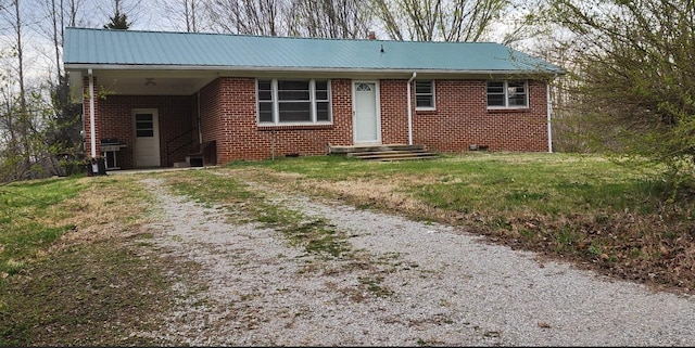ranch-style house featuring a carport, metal roof, a front yard, brick siding, and driveway