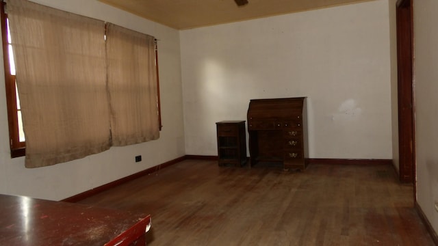 spare room featuring baseboards and wood finished floors