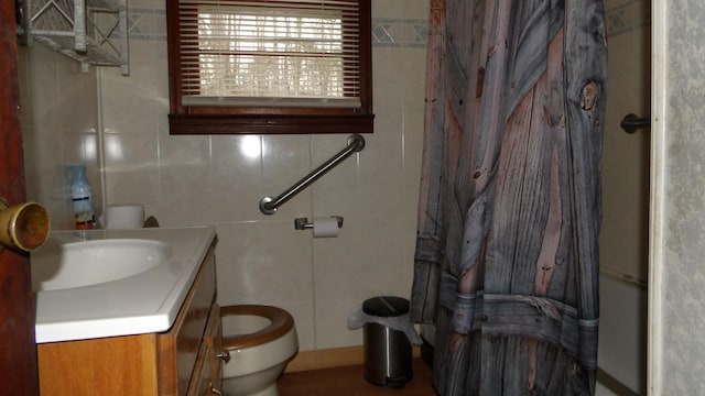 full bathroom with toilet, vanity, and tile walls
