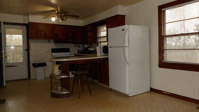 kitchen with a wealth of natural light, freestanding refrigerator, ceiling fan, and under cabinet range hood