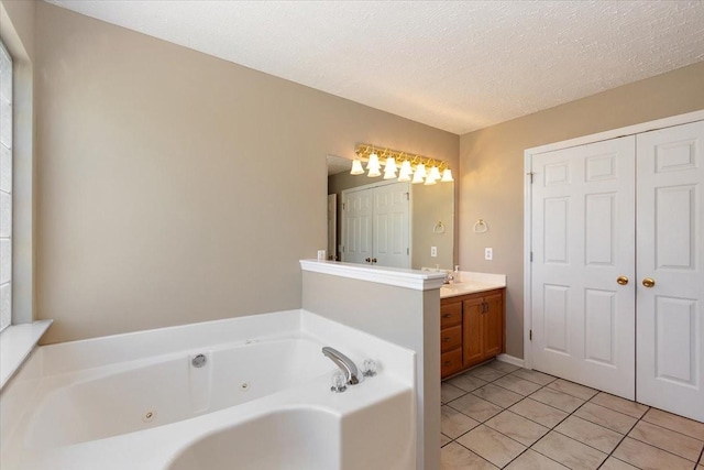 bathroom featuring vanity, tile patterned floors, a textured ceiling, and a jetted tub