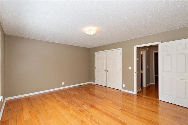 unfurnished bedroom featuring light wood-style flooring, a textured ceiling, and baseboards