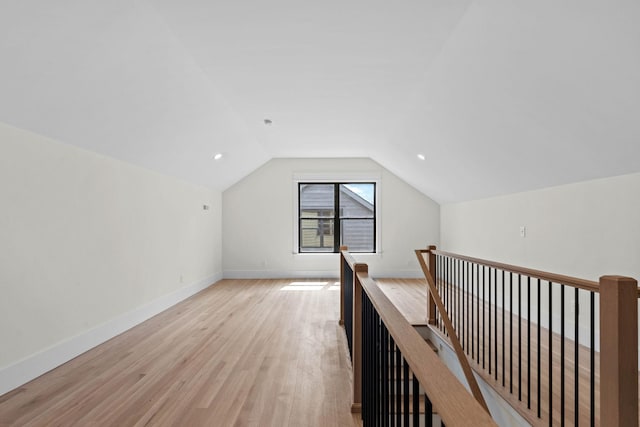 additional living space with baseboards, light wood-type flooring, and lofted ceiling