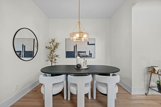 dining area with baseboards, a chandelier, and light wood-style floors
