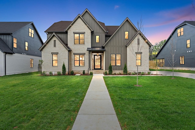 modern inspired farmhouse with board and batten siding, a front yard, and brick siding