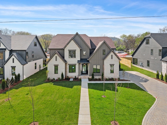 modern farmhouse featuring a shingled roof, driveway, board and batten siding, and a front lawn