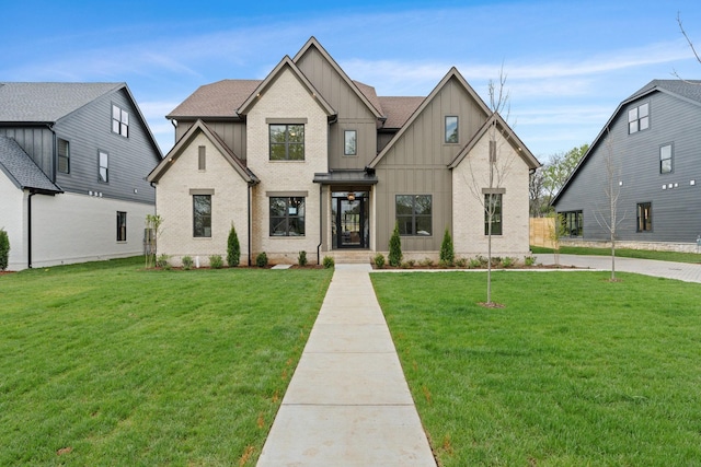 modern inspired farmhouse with roof with shingles, a front yard, brick siding, and board and batten siding
