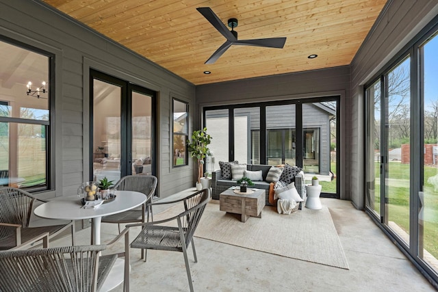 sunroom featuring outdoor lounge area, wooden ceiling, ceiling fan with notable chandelier, and concrete flooring