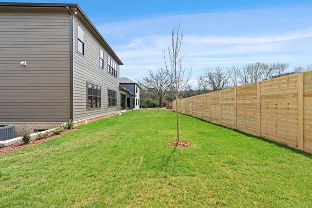 view of yard with central air condition unit and a fenced backyard
