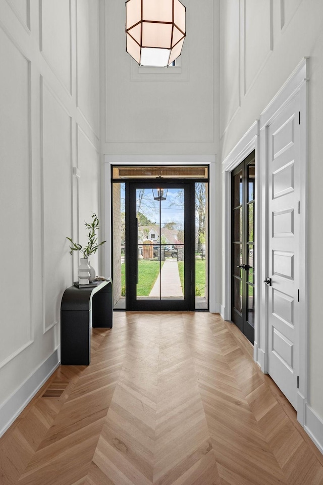 entryway with a decorative wall, a high ceiling, and baseboards