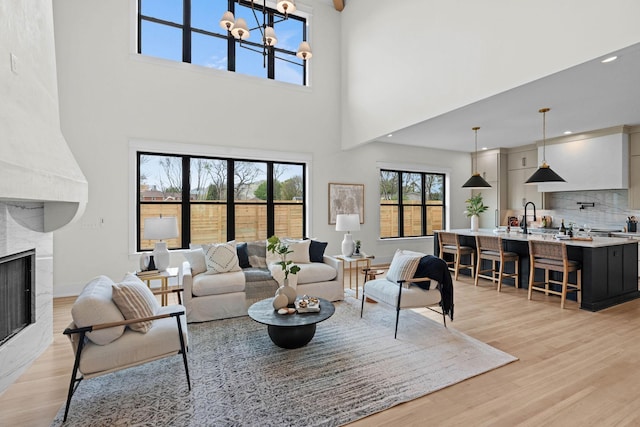 living room featuring light wood finished floors, a fireplace, baseboards, and recessed lighting