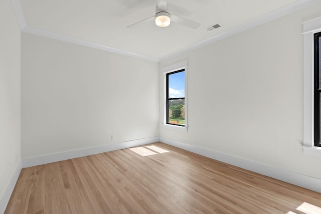 spare room featuring light wood finished floors, baseboards, ornamental molding, and visible vents