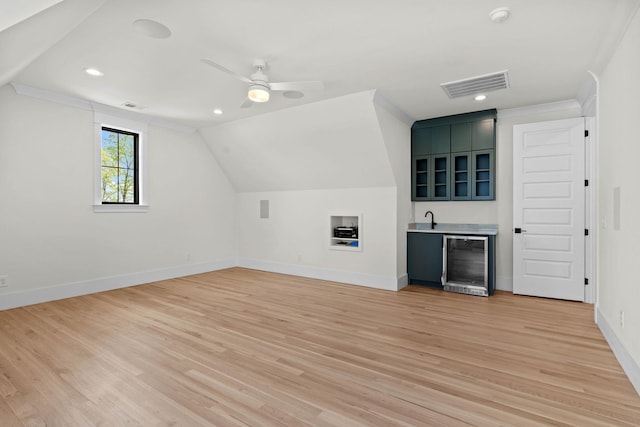 additional living space with light wood-style floors, indoor wet bar, visible vents, and wine cooler
