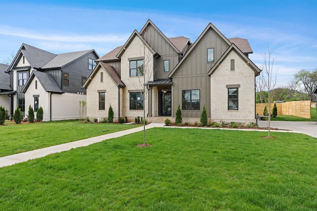 modern inspired farmhouse with board and batten siding, a front yard, fence, brick siding, and a shingled roof