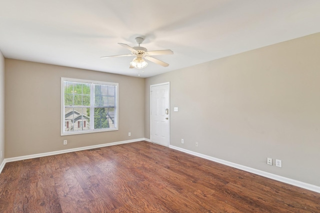 empty room featuring dark wood-type flooring, visible vents, baseboards, and ceiling fan