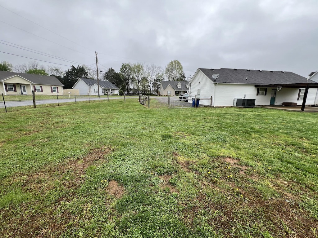 view of yard with central AC and fence