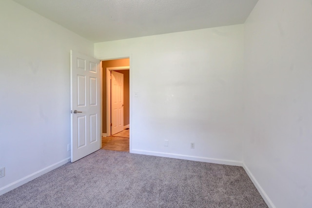 spare room featuring carpet floors and baseboards