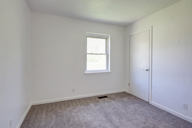 unfurnished room featuring baseboards, visible vents, and carpet