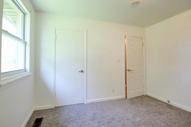 unfurnished bedroom featuring visible vents, carpet, and multiple windows